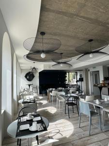 a dining room with tables and chairs and lights at Pavillon de la plage in Trébeurden