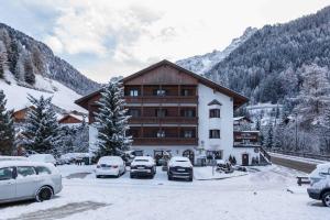 a large building with cars parked in the snow at Hotel Casa Alpina - Alpin Haus in Selva di Val Gardena