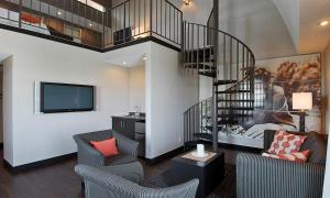 a living room with a staircase and a tv at Ramada Plaza by Wyndham West Hollywood Hotel & Suites in Los Angeles