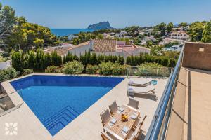 ein Swimmingpool mit Stühlen und ein Haus in der Unterkunft Villa Alex by Abahana Villas in Benissa