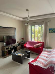a living room with a red couch and a tv at Casa 3Jotas in Garopaba
