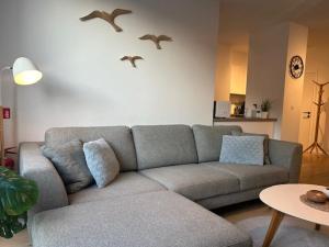 a living room with a couch and birds flying above it at Quality Time appartement met gesloten garagebox in De Panne