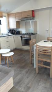 kuchnia z białymi szafkami, stołem i krzesłami w obiekcie MH 538 TOUT EQUIPE et TOUT CONFORT 2ch 1sdb dans camping 4 étoiles w mieście Saint-Julien-en-Born