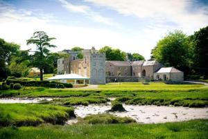 a large castle with a river in front of it at Ship Cottage Tenby Beach 50m in Pembrokeshire