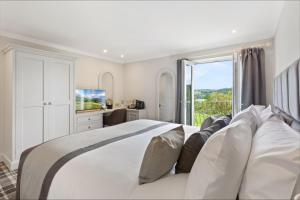 a white bedroom with a large bed and a window at The Ryebeck Hotel in Bowness-on-Windermere