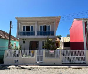 a white fence in front of a house at Casa 3Jotas in Garopaba