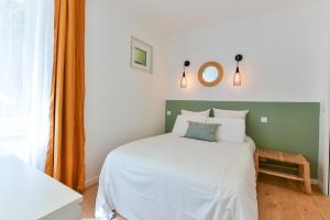 sypialnia z białym łóżkiem z zielonym zagłówkiem w obiekcie L'EMERAUDE duplex confortable au cœur de Cannes, proche plage du Midi et Palais w Cannes