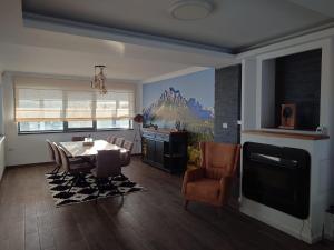 a living room with a dining table and a tv at Alpine Blu - Horezu - Varful lui Roman - Sauna, Hot Tub & Gym in Horezu