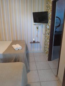 a hotel room with two beds and a flat screen tv at Pousada da Sami in Barra de São Miguel