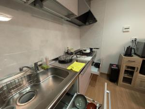 a kitchen with a stainless steel sink and a stove at お宿みとしる in Mito