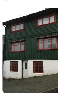 Un edificio verde y blanco con ventanas rojas en Vindmølle, en Stavanger