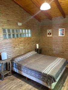 a bedroom with a bed and a brick wall at Casa Caviahue in Villa Carlos Paz