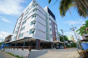 a tall white building on a street with a palm tree at Sritrang Place in Hat Yai