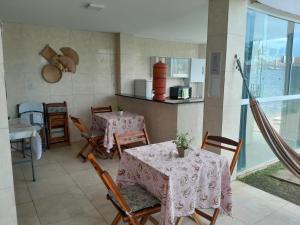 a dining room with two tables and a kitchen at Pousada da Sami in Barra de São Miguel