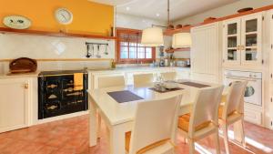 a kitchen with a white table and white chairs at Casa Cerralba Pizarra by Ruralidays in Pizarra
