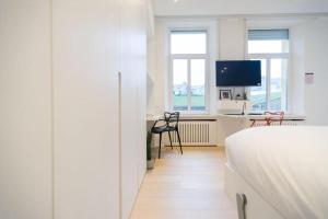 a bedroom with a bed and a desk with a tv at Studio Fischer à la Pétrusse 302 in Luxembourg