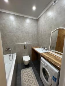 a bathroom with a toilet sink and a washing machine at Квартира in Taldykolʼ