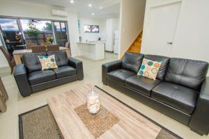 a living room with black leather couches and a table at Agnes Sails in Agnes Water