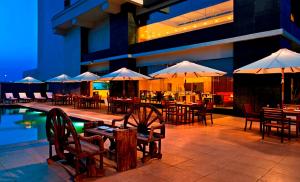 um restaurante com mesas e guarda-sóis ao lado de uma piscina em Red Fox Hotel Bhiwadi em Bhiwadi