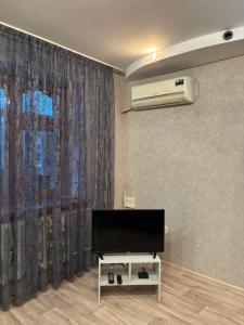 a living room with a flat screen tv in front of a window at Однокомнатная квартира in Uralsk