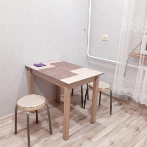 a table with two stools and a table and chairs at Однокомнатная квартира in Uralsk +4 photos