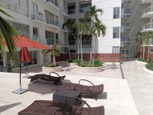 Un patio con bancos y sombrillas frente a un edificio. en Boca del Mar III, apartamento 706A, en Boca Chica