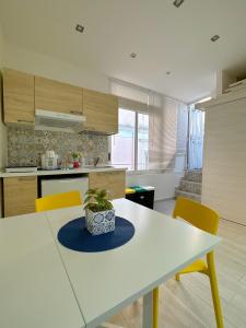 a kitchen with a white table and yellow chairs at Le casette di PaMi in Gaeta