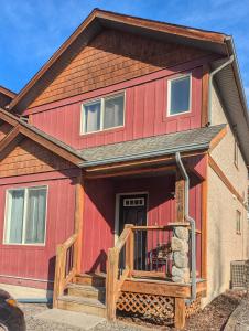 a red house with a wooden porch and a deck at Bright 3 bed 3 bath House in Radium Hot Springs in Radium Hot Springs