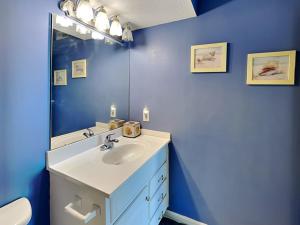 a blue bathroom with a sink and a mirror at Poolside Paradise in North Topsail Beach