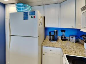 a kitchen with white cabinets and a white refrigerator at Poolside Paradise in North Topsail Beach