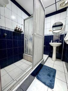 y baño de azulejos azules con ducha y lavamanos. en SC Central Suite, en Manta 9 fotos más