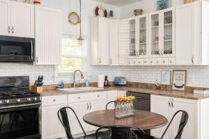 una cucina con mobili bianchi e un tavolo con sedie di The Little Haven - Charming Coastal Cottage a South Haven Altre 16 foto