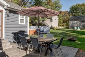 un tavolo e sedie con un ombrellone in un patio di The Little Haven - Charming Coastal Cottage a South Haven