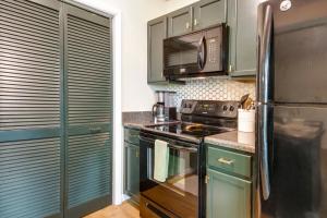 a kitchen with green cabinets and a black refrigerator at Wintergreen Resort Condo with Deck, 0 3 Mi to Slopes in Lyndhurst