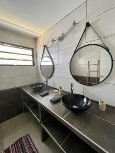 une salle de bain avec deux lavabos et un grand miroir dans l'établissement Kaza Jolan à Sainte Anne, à Sainte-Anne