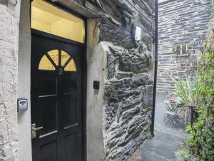 a black door on a stone building with a patio at The Old Cornhill in Porthmadog
