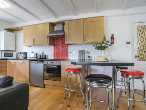 a kitchen with wooden cabinets and bar stools at The Old Cornhill in Porthmadog +17 photos
