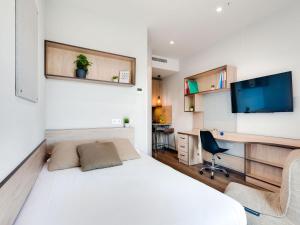 圣塞瓦斯蒂安Livensa Living Studios San Sebastián的一间卧室，配有一张床、一张书桌和一台电视