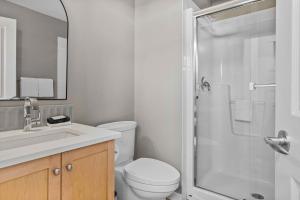 a white bathroom with a toilet and a shower at Freshly Remodeled - 2 King Beds- Breathtaking Views in Canmore