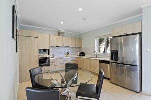 una cucina con tavolo in vetro e sedie di Eagle Beach- Private pool- LeVent townhome-LV106th a Palm Beach