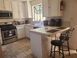 a kitchen with white cabinets and a counter with two stools at 3BR & Loft near Palmdale Hospital- Shared Hm in Palmdale