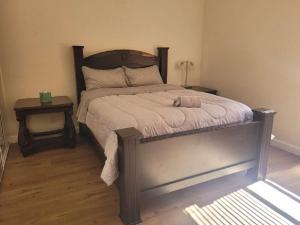 a bedroom with a bed with a wooden headboard and two tables at 3BR & Loft near Palmdale Hospital- Shared Hm in Palmdale