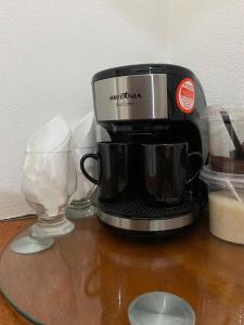 eine Kaffeemaschine und zwei Gläser auf einem Tisch in der Unterkunft Hospedaria Porto de Paz 2 in Cunha