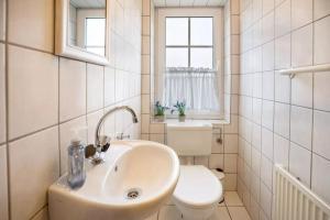 a bathroom with a sink and a toilet and a window at Haus Clara in Neßmersiel