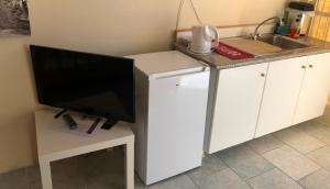 a small kitchen with a tv on a white desk at Converted Shed Studio & Garden Hanging Bed in Porto Rafti