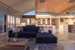 Una sala de estar con un sofá azul y una mesa. en Penthouse with a view to die for!, en Ciudad del Cabo