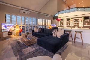 Una sala de estar con un sofá y un bar. en Penthouse with a view to die for!, en Ciudad del Cabo