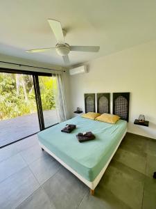 une chambre avec un grand lit avec un ventilateur de plafond dans l'établissement Kaza Jolan à Sainte Anne, à Sainte-Anne