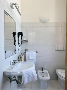 a white bathroom with a sink and a toilet at Al Gallo Trattoria e Locanda in Alfonsine