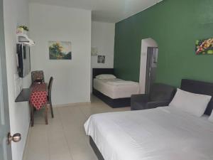 Una habitación de hotel con una cama, una silla y un escritorio. en Langkawi Western Motel, en Pantai Cenang